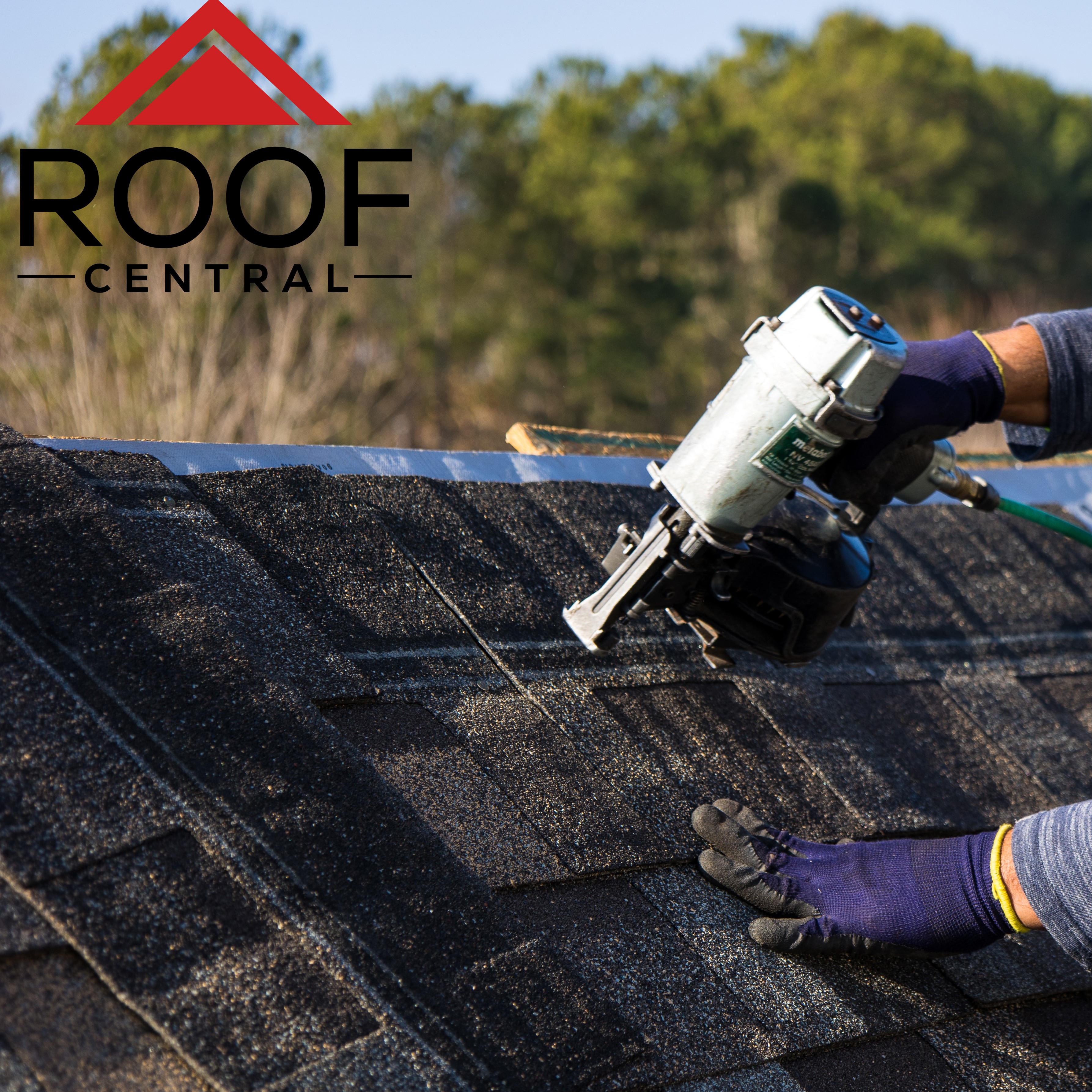 Asphalt shingles being installed on a roof with a nail gun.